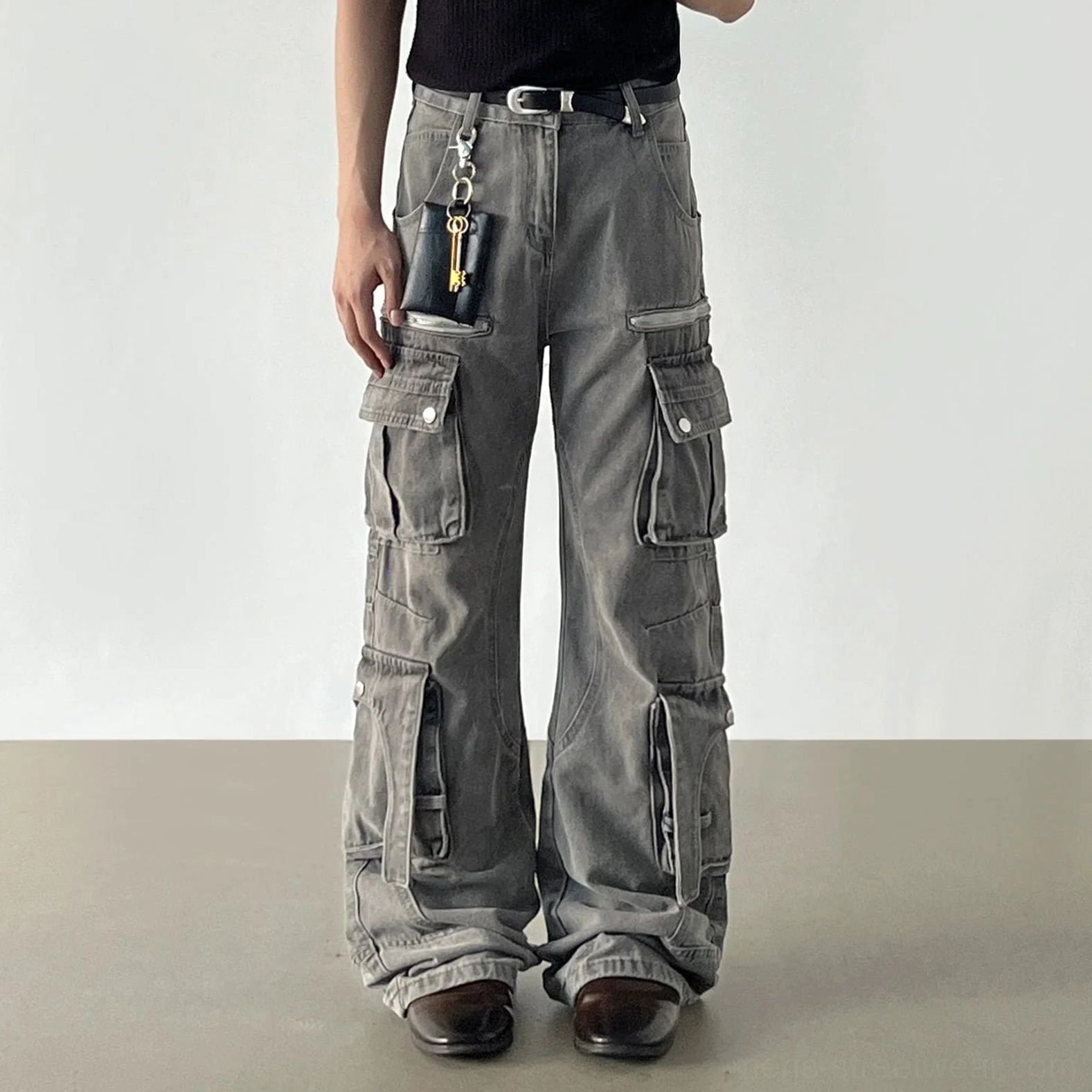 Faded grey multi-pocket cargo denim jeans worn from the front featuring wide legs, utility pockets, and zipper accents