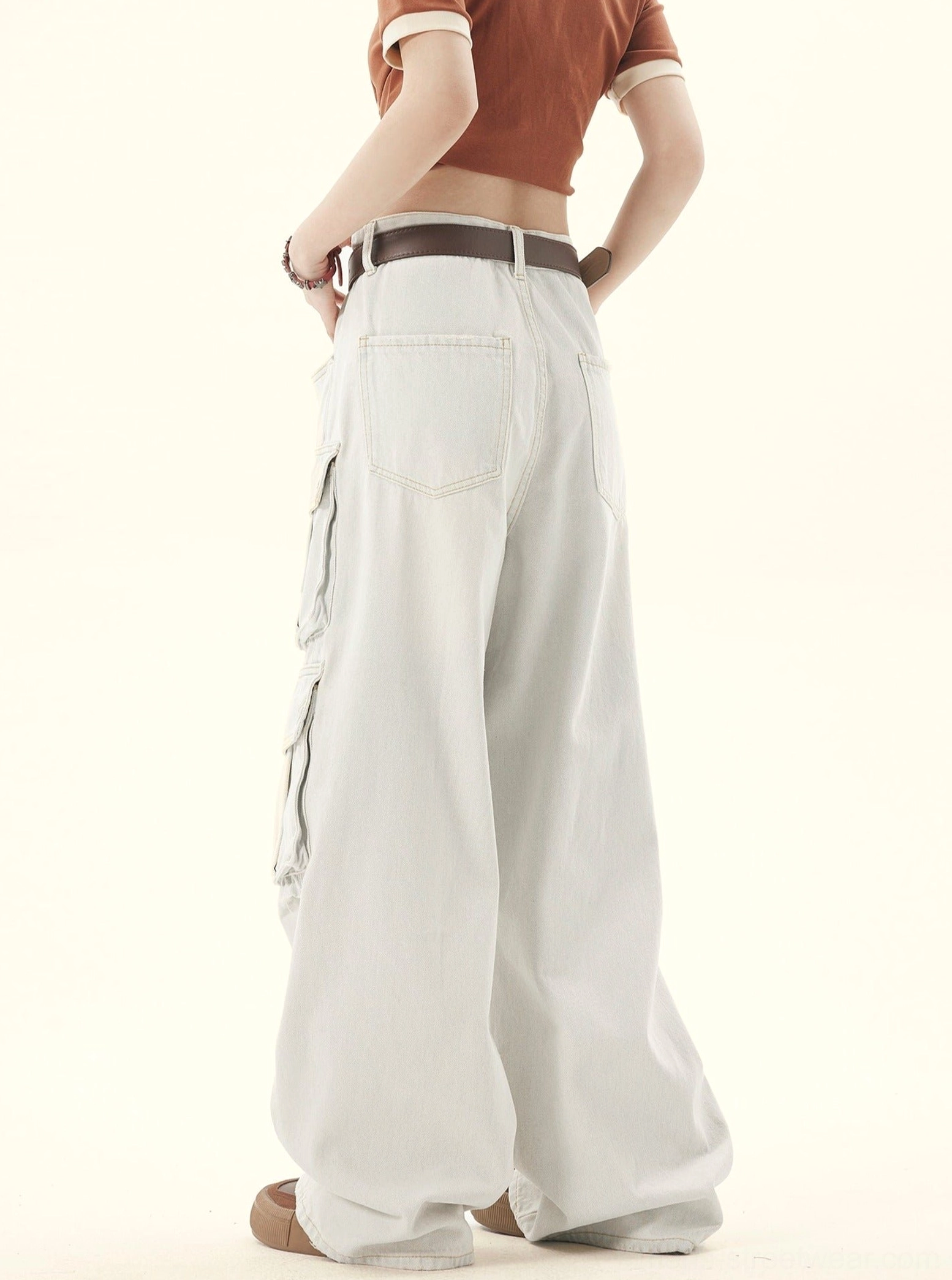 Three-quarter back view of faded off-white denim cargo pants showing wide legs and rear utility pocket details