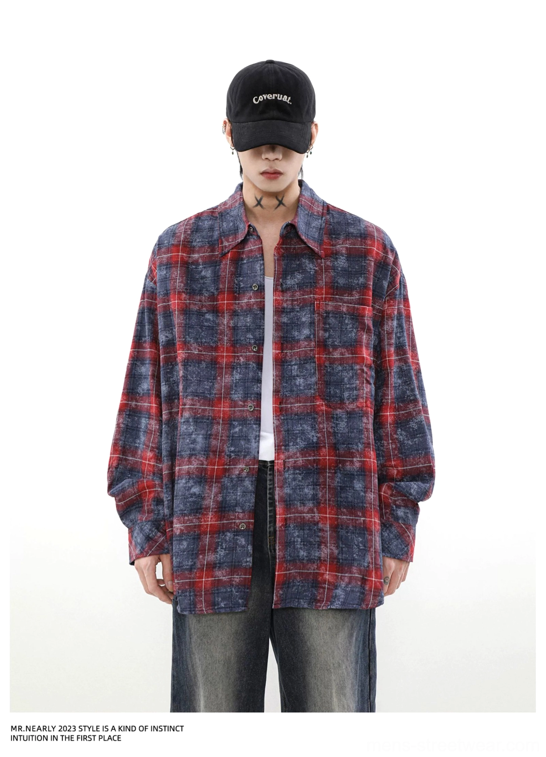 Model wearing a faded plaid overshirt over a white tee with dark jeans and baseball cap in casual Seoul-inspired streetwear