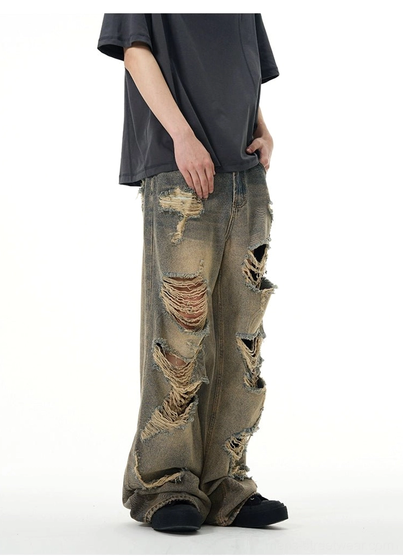 Three-quarter view of faded retro washed wide-leg ripped jeans with asymmetric shredded holes and raw denim texture