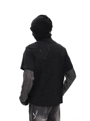 Rear full-body view of a black Faultline diagonal zip layered tee with crack print, sheer mesh long sleeves, beanie, gloves and graffiti flared jeans in Korean streetwear styling