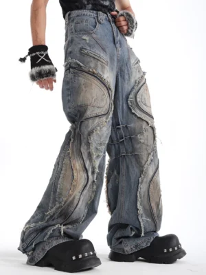 Left three-quarter view of relaxed wide-leg vintage denim jeans featuring exposed frayed seams decorative zippers and punk streetwear details
