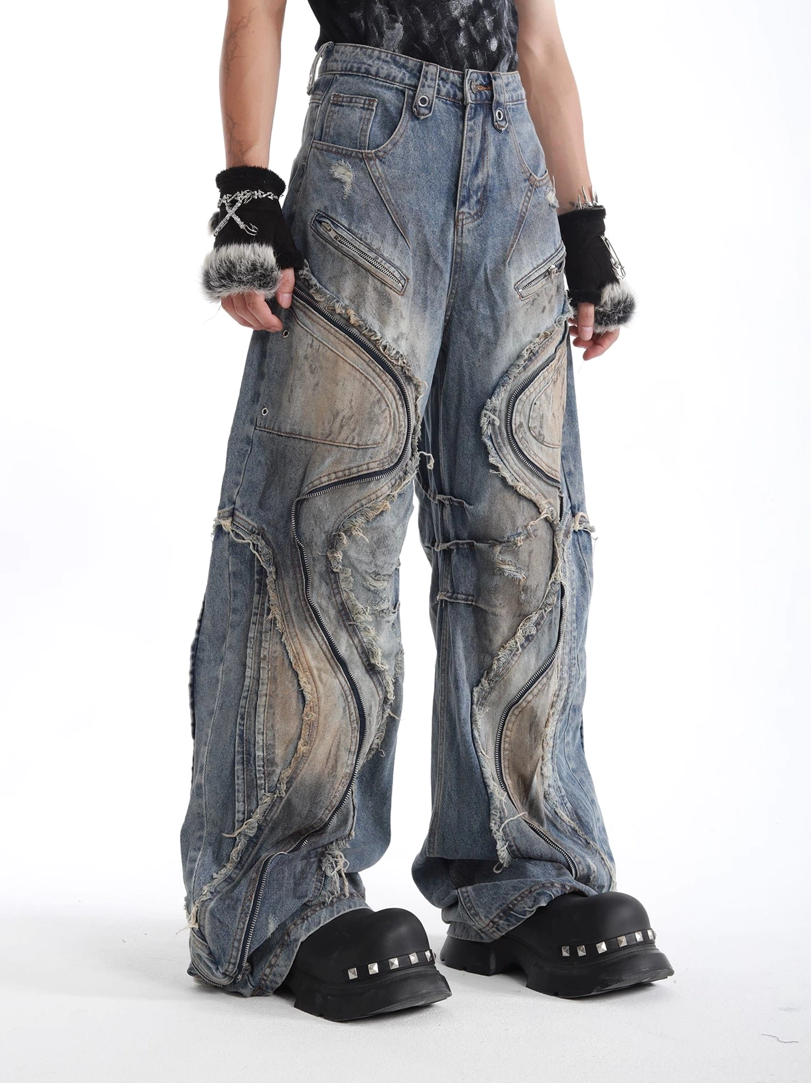 Front three-quarter view of washed blue wide-leg denim jeans with visible panel stitching zippered pockets and distressed vintage streetwear finish