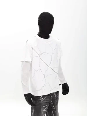 Three-quarter rear view of a white Faultline diagonal zip layered graphic tee with cracked print, silver zipper and sheer mesh sleeves styled with graffiti denim