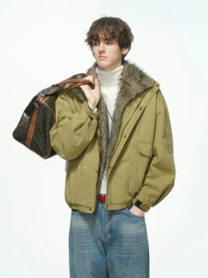 Three-quarter view of a khaki olive washed canvas faux fur collar cropped parka jacket styled with a high-neck top baggy jeans and vintage travel bag