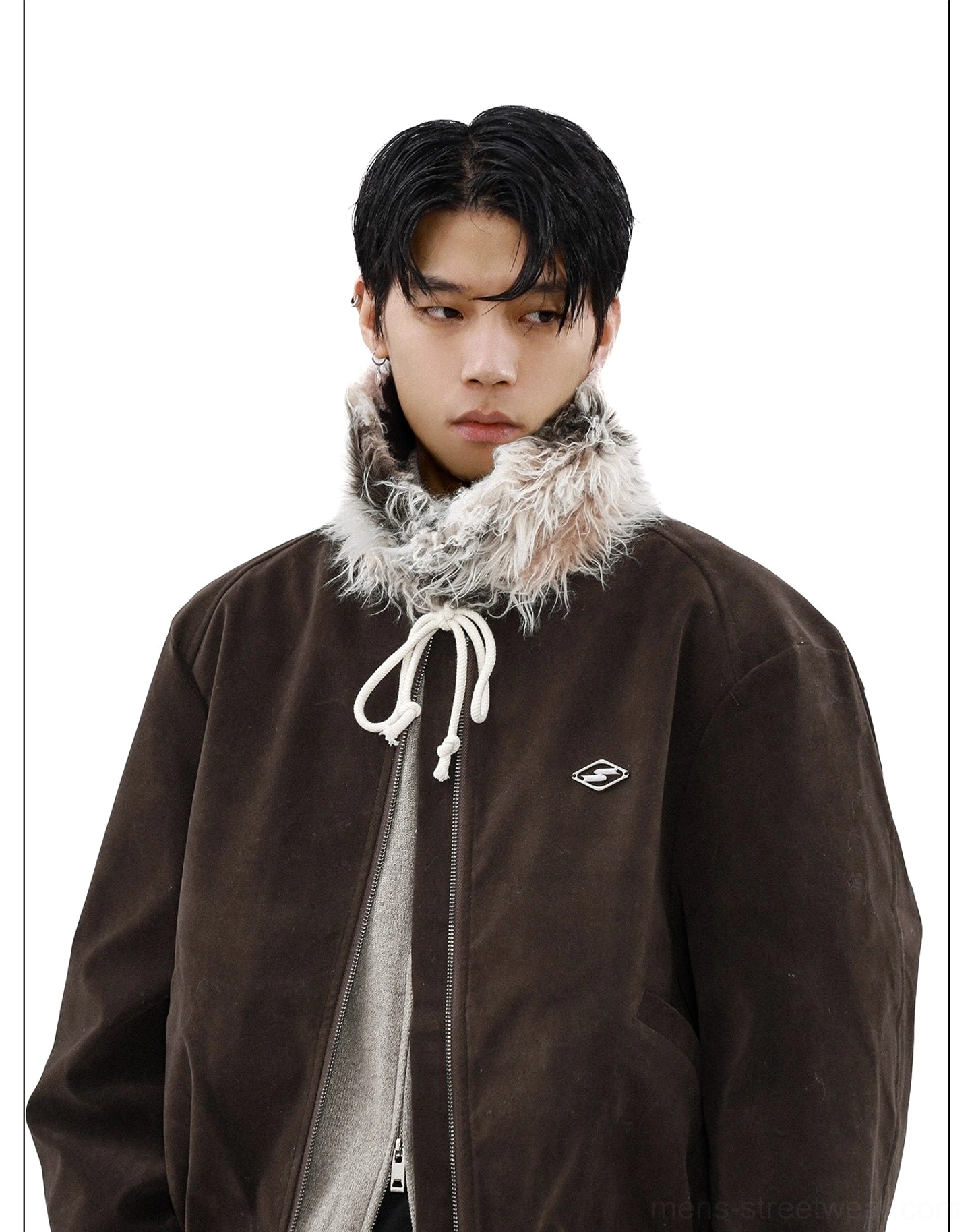 Close-up of dark brown suede bomber jacket faux fur collar chest badge and layered winter styling