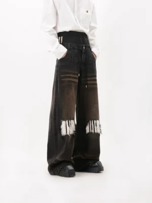 Left three quarter view of washed black faux fur patch wide leg jeans with gradient denim, distressed furry knees, layered waistband, white shirt and chunky platform shoes