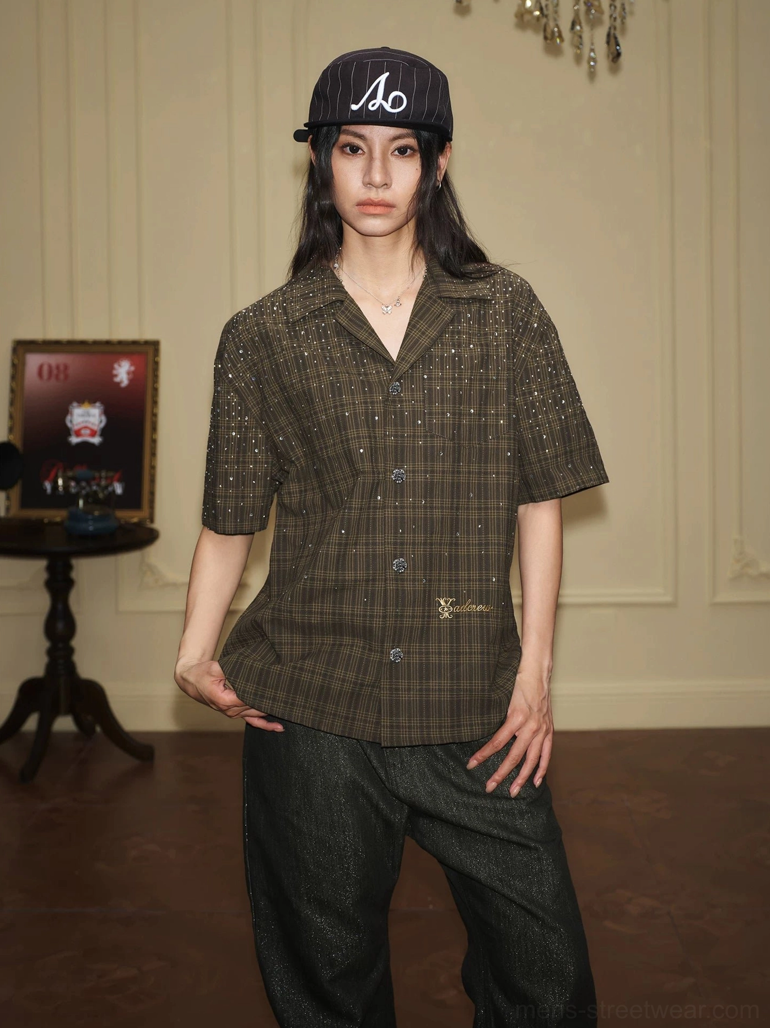 Female model wearing a dark olive plaid rhinestone camp collar shirt with short sleeves and embroidered script detail