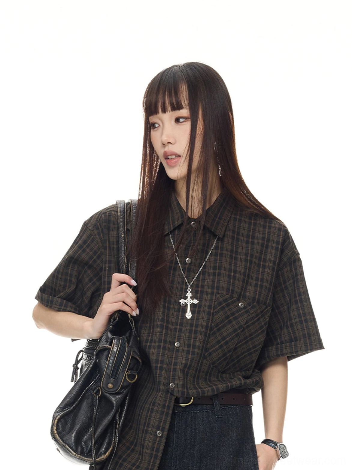 Female model wearing a loose vintage plaid short sleeve shirt with a black leather shoulder bag, belt, and cross necklace