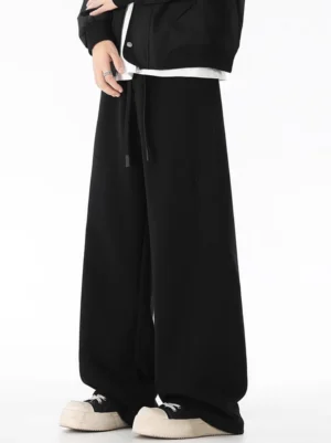 Black wide-leg fleece sweatpants shown in a front three-quarter Korean streetwear outfit with a black jacket, white tee, drawstring waist, and platform sneakers