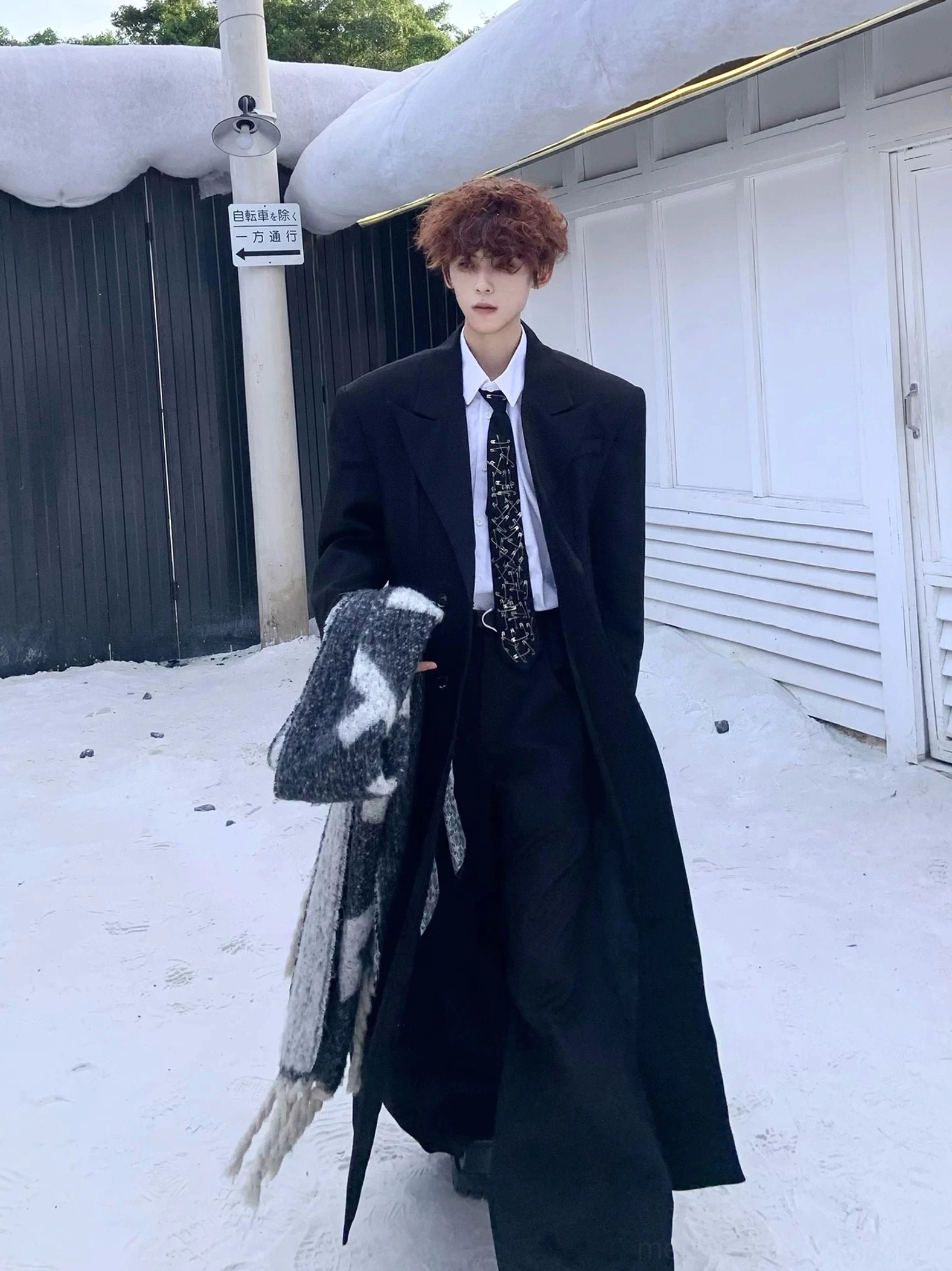 Flowing oversized black full-length overcoat in motion with white shirt tie and winter scarf styling