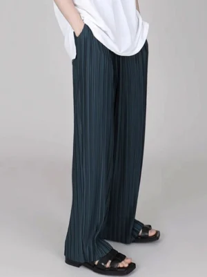Forest green ice silk pleated wide-leg pants worn with white t-shirt and black slide sandals front close-up
