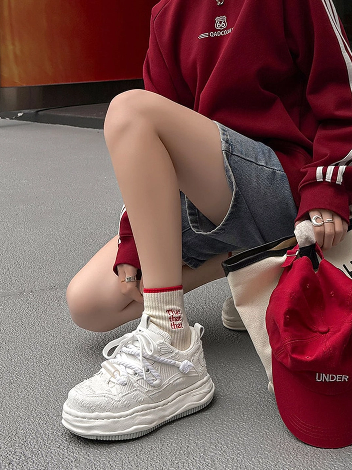 Low-angle view of a frayed canvas platform sneaker worn with denim shorts and printed socks in a relaxed Korean streetwear outfit