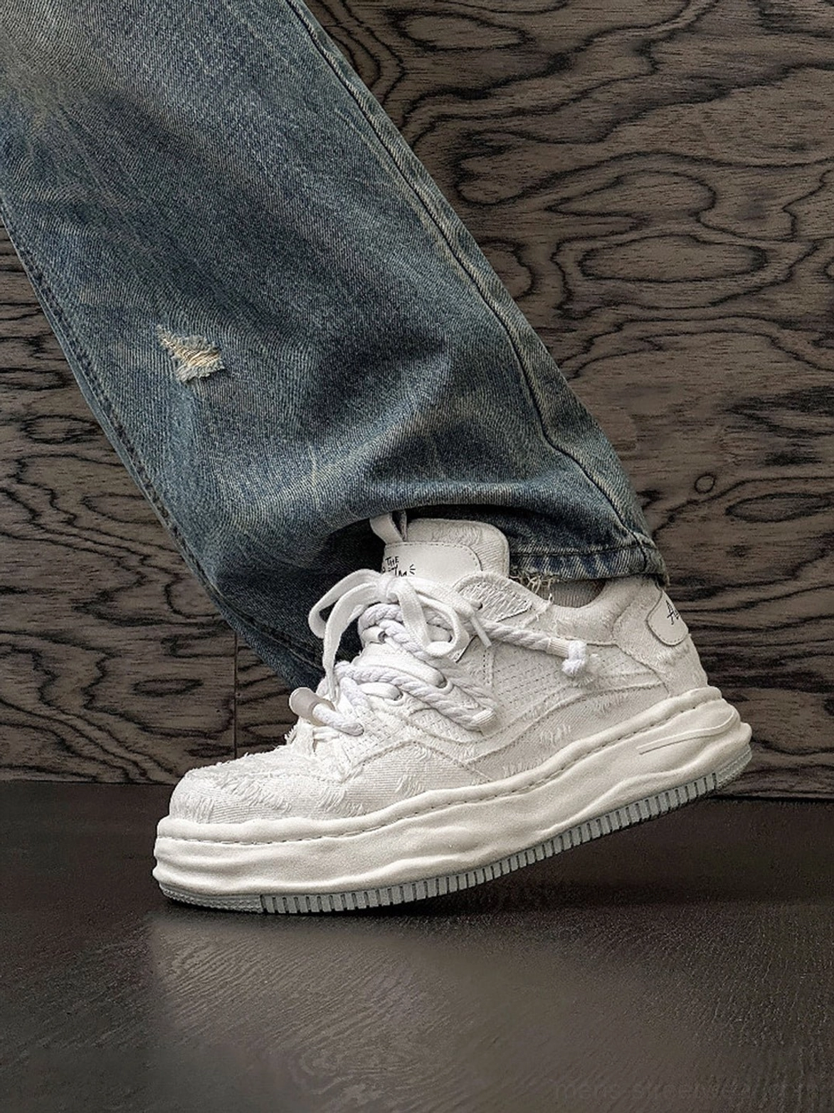 Side view of light off-white frayed canvas platform sneakers worn with distressed straight-leg denim and layered casual streetwear