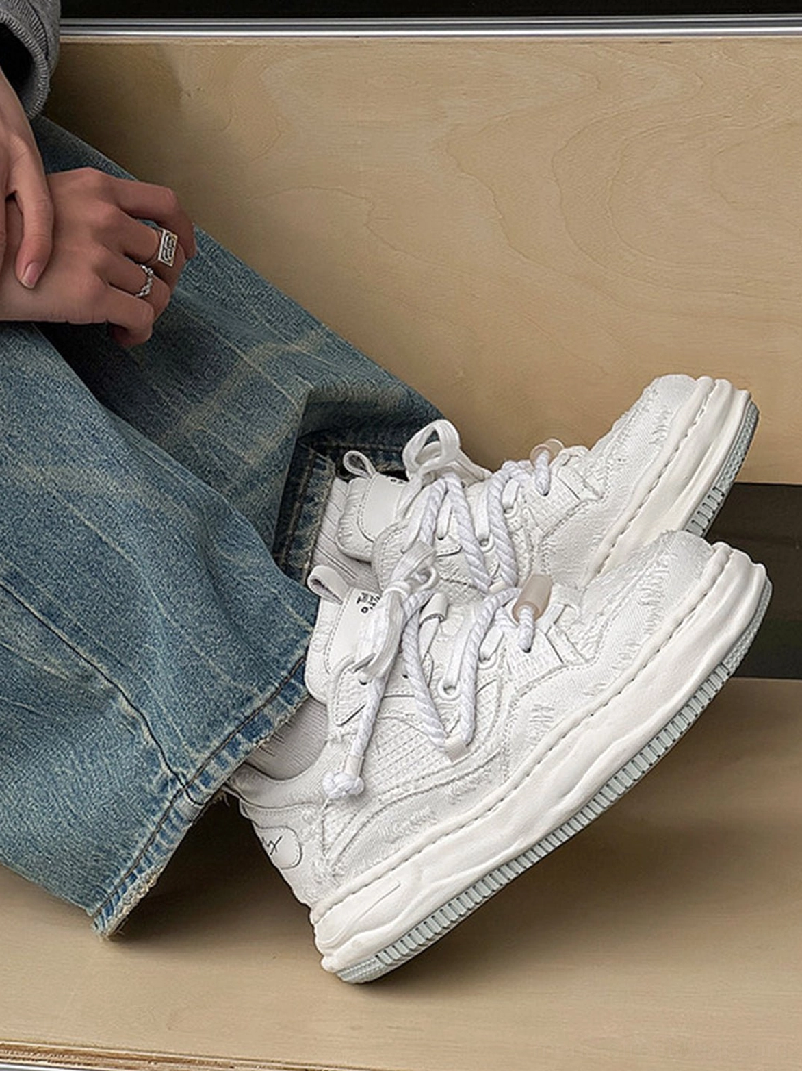 Pair of frayed canvas platform sneakers displayed on a wooden table with denim jeans and layered East Asian streetwear accessories