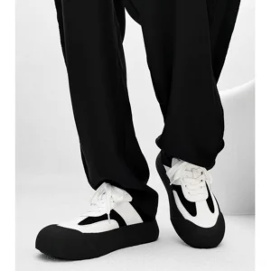 Front low angle view of vintage chunky sneakers worn with black cargo pants, highlighting the rounded toe, bold black and white color blocking, and thick platform sole