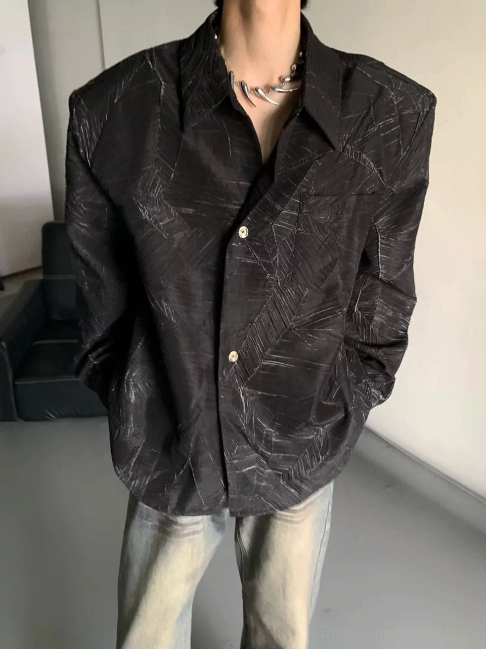 Close-up of black oversized leaf print streetwear shirt with grey botanical lines and metal buttons