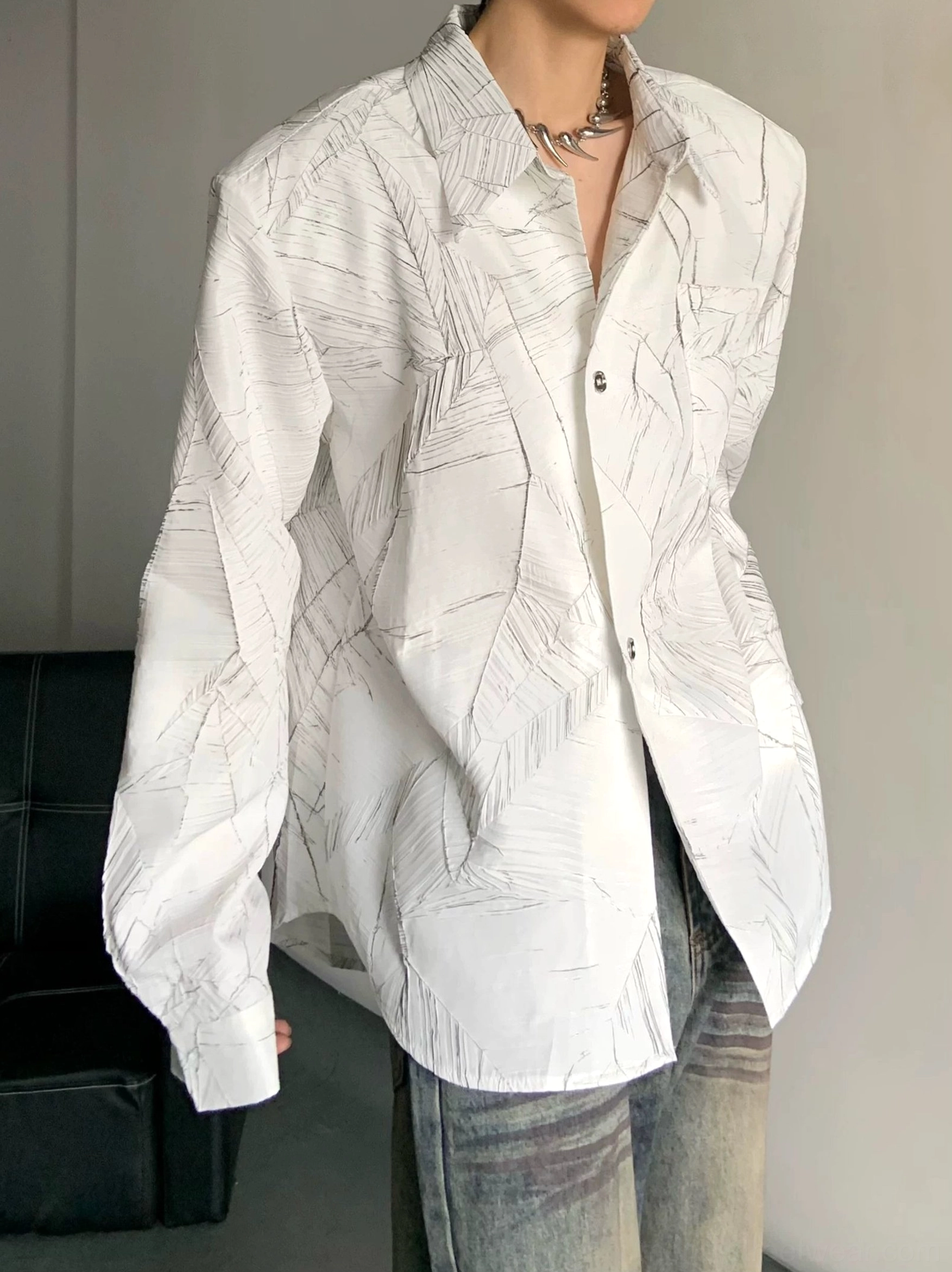Close-up white oversized long sleeve leaf print shirt with smooth fabric and buttoned placket