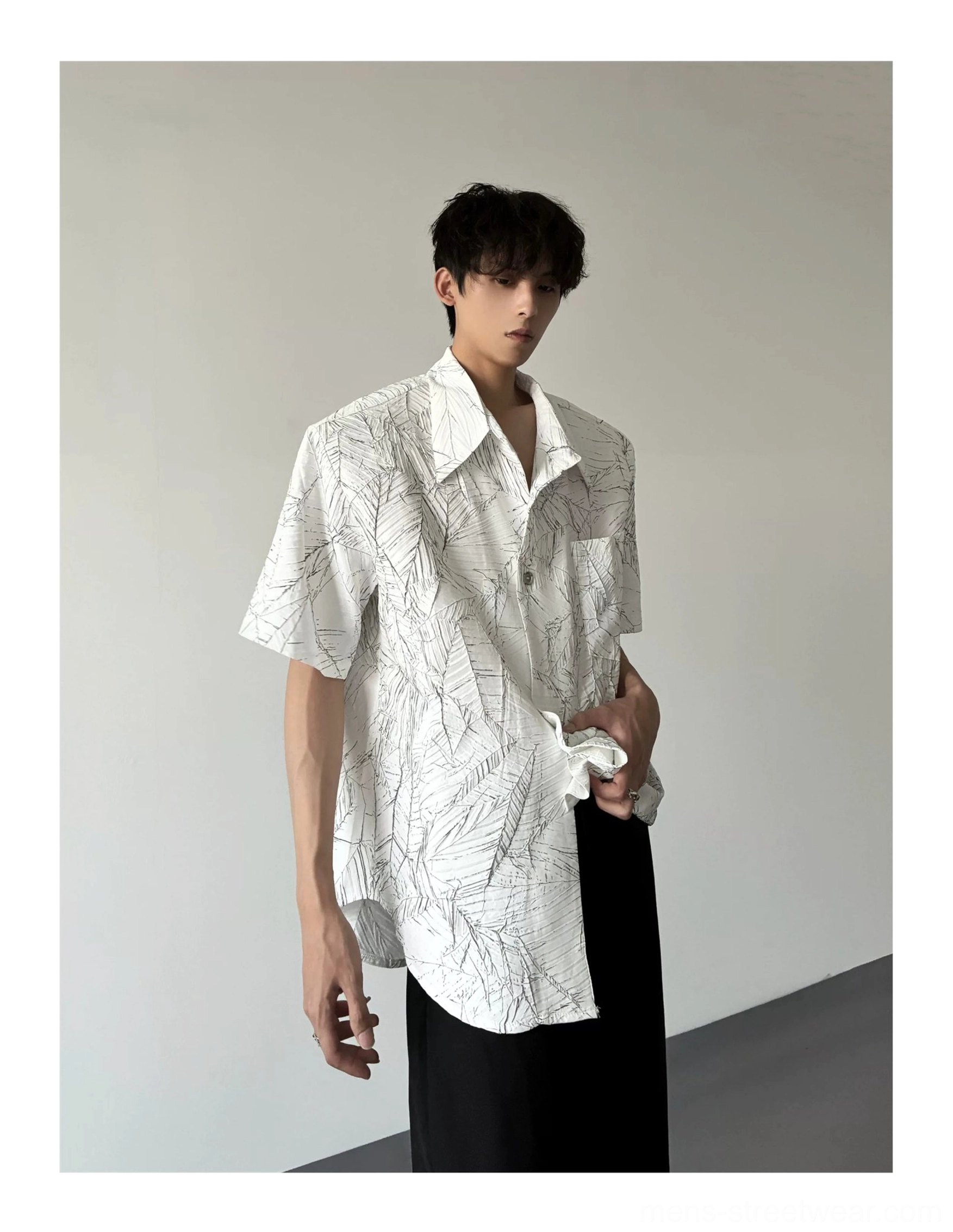White oversized short sleeve leaf print shirt shown from a three-quarter angle with pointed collar