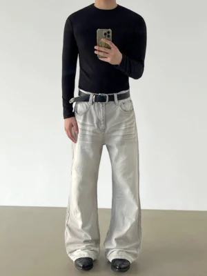 Front view of washed light grey wide-leg jeans styled with a black ribbed top leather belt and leather shoes in a minimalist studio