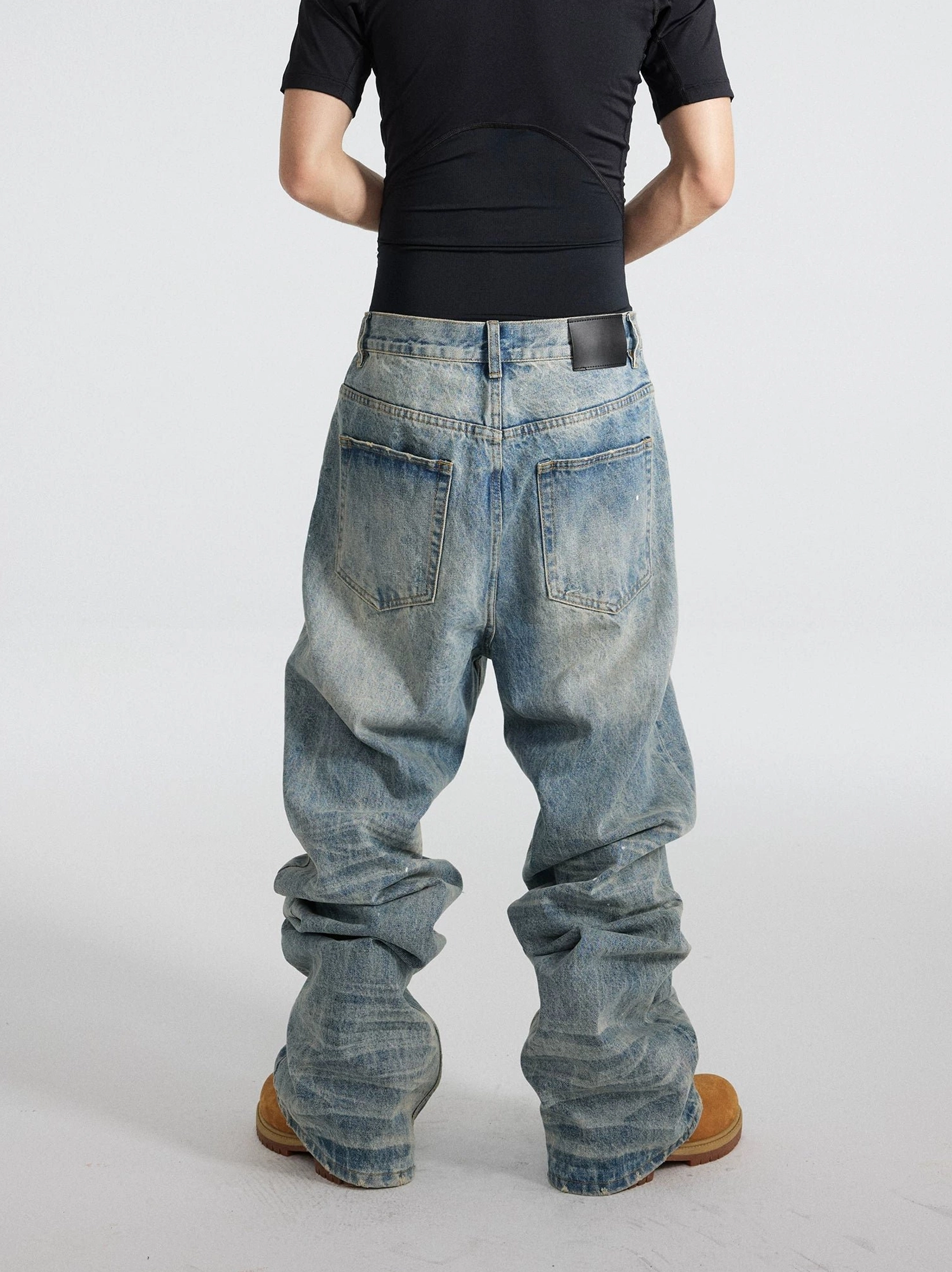 Rear view of distressed blue wide-leg streetwear jeans showing faded wash, classic back pockets, and stacked baggy legs