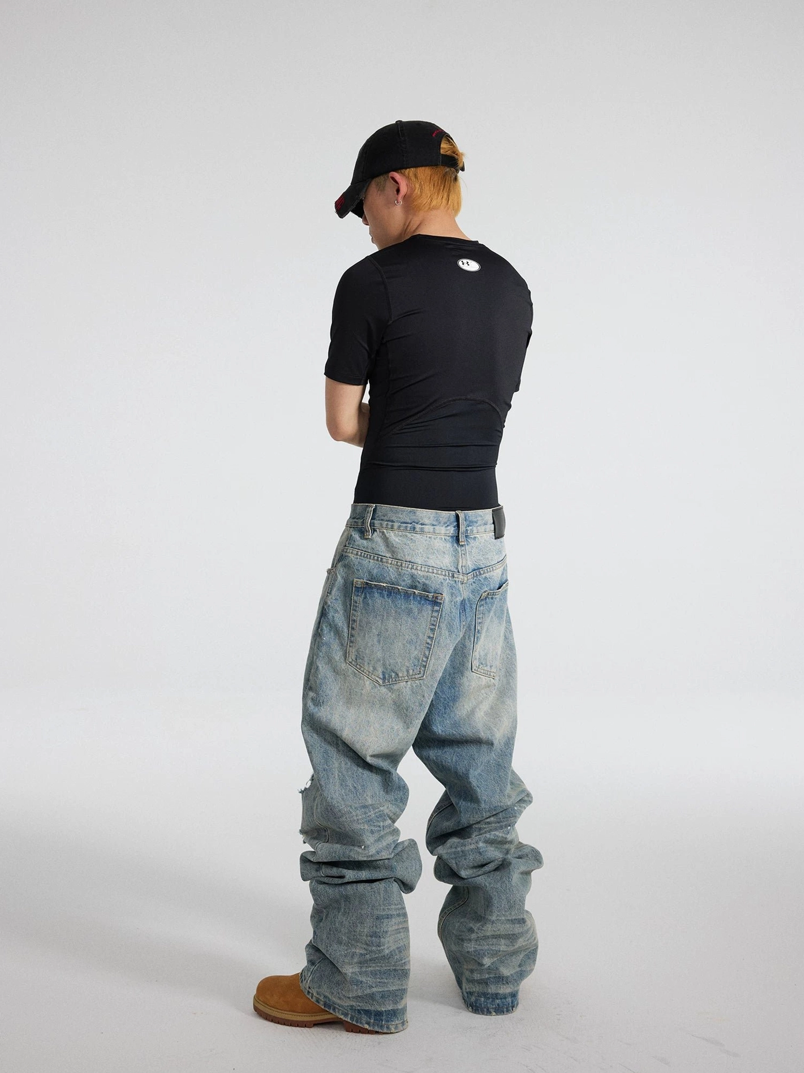 Side rear view of light blue distressed baggy jeans with relaxed straight wide-leg fit and long stacked hems