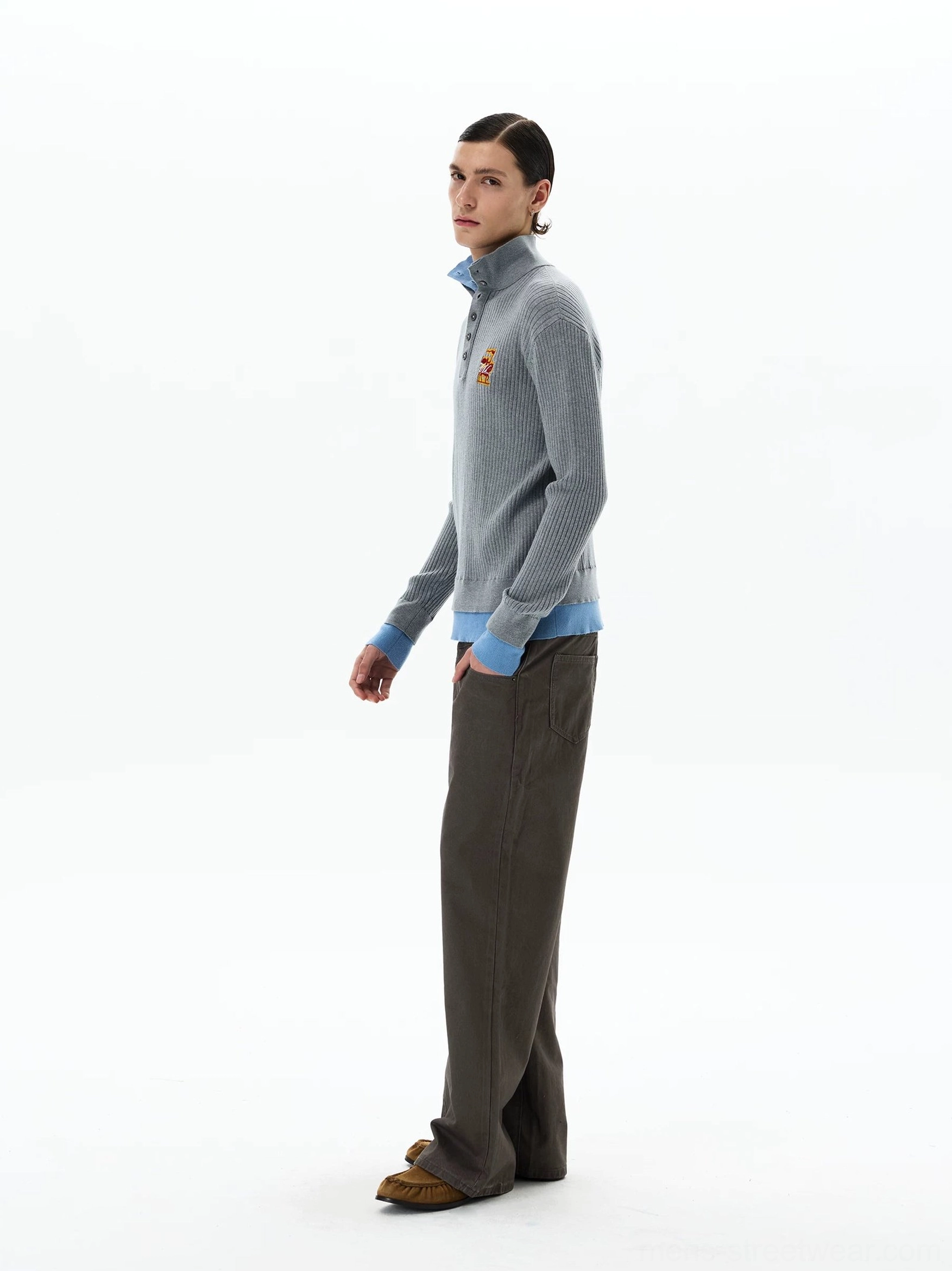 Side view of men's grey ribbed knit polo sweater featuring sky blue layered collar cuffs and hem with brown trousers and loafers