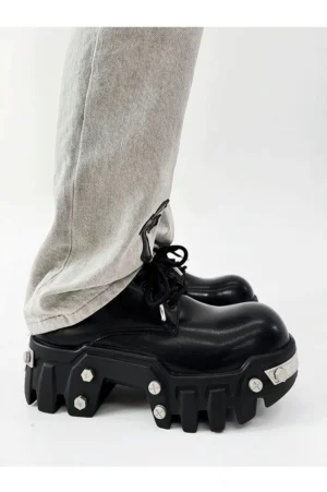 Futuristic black 8cm platform Oxford shoes worn with light gray cross embroidered jeans in a low side streetwear view