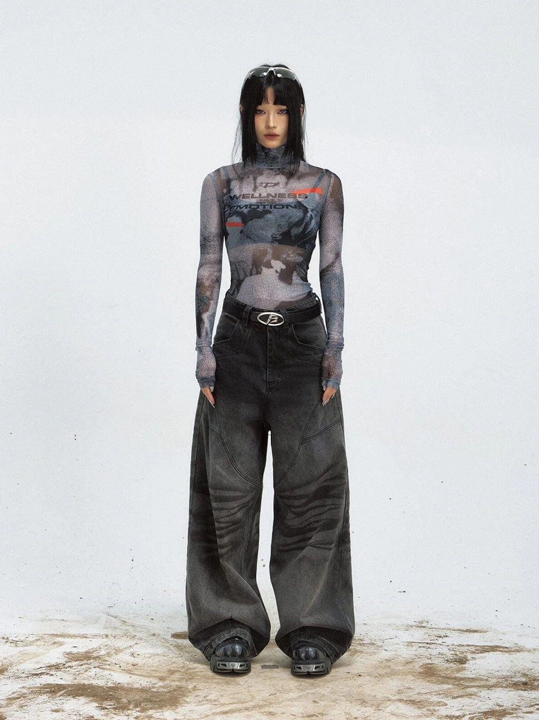 Front view of a futuristic graphic printed mesh turtleneck top styled with black wide-leg streetwear jeans