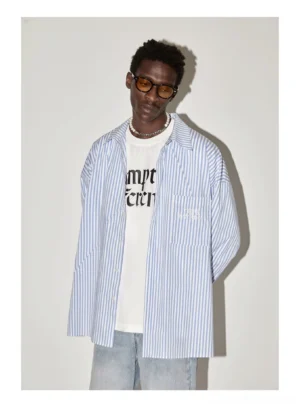 Black male model wearing a light blue oversized striped shirt over a graphic tee with relaxed jeans in a Korean streetwear outfit