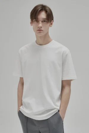 White GIZA 45 cotton short sleeve crew neck T-shirt styled with grey trousers and white sneakers in a minimalist studio