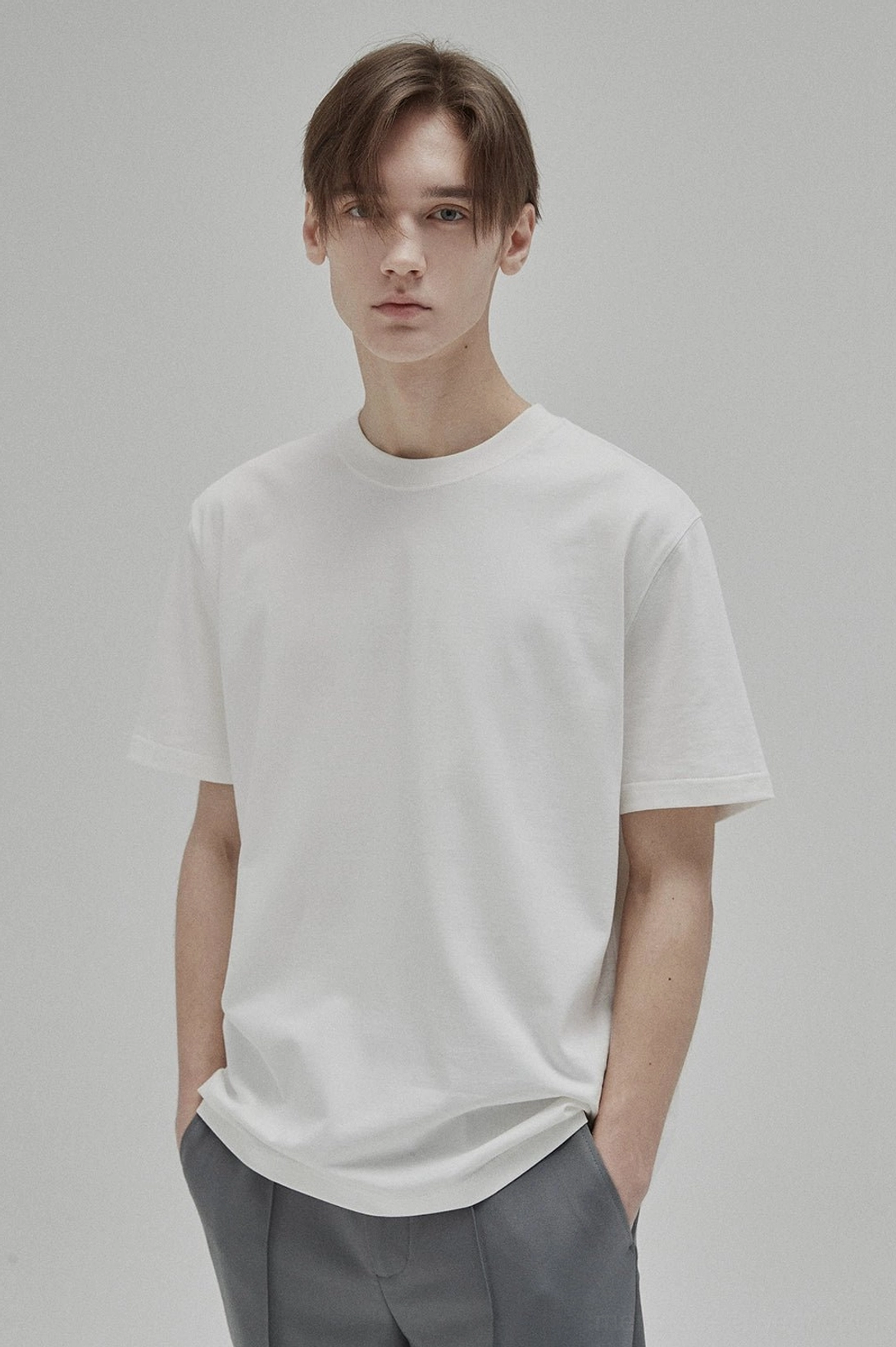 White GIZA 45 cotton short sleeve crew neck T-shirt styled with grey trousers and white sneakers in a minimalist studio