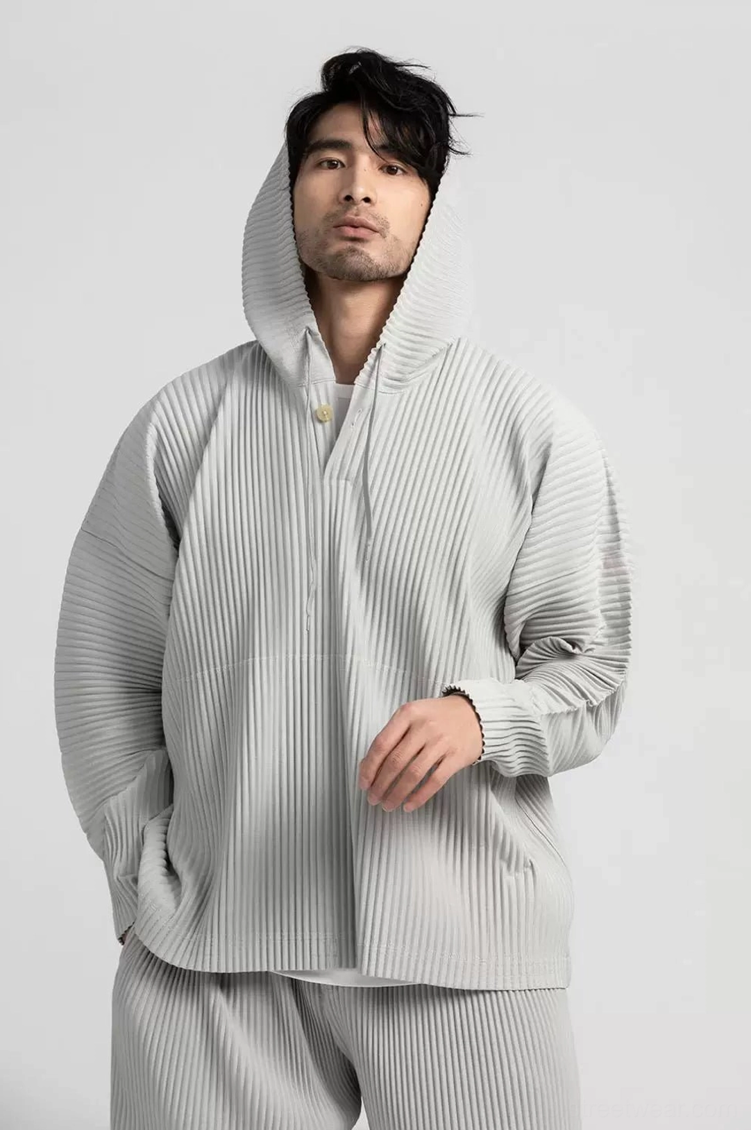 Men's grey pleated hoodie and trousers set shown in a three-quarter front view with clean minimalist urban styling