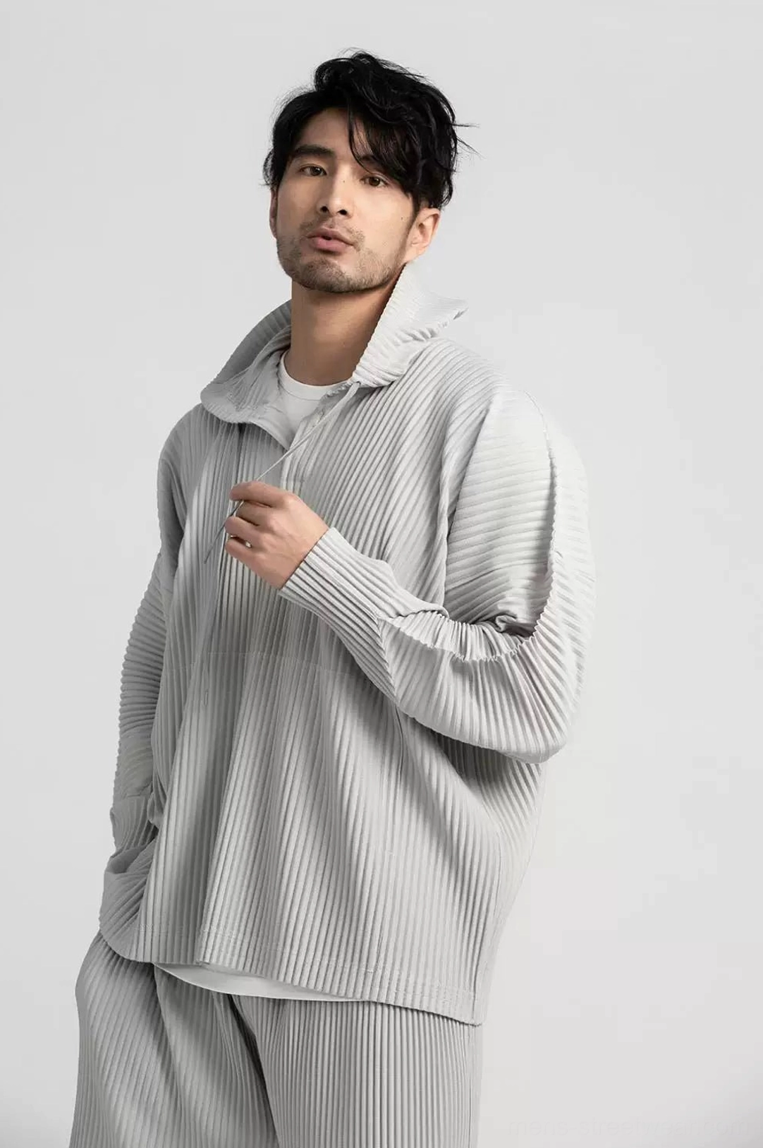 Grey pleated hoodie and matching trousers set shown from a three-quarter angle with relaxed Korean fashion proportions and pocket styling