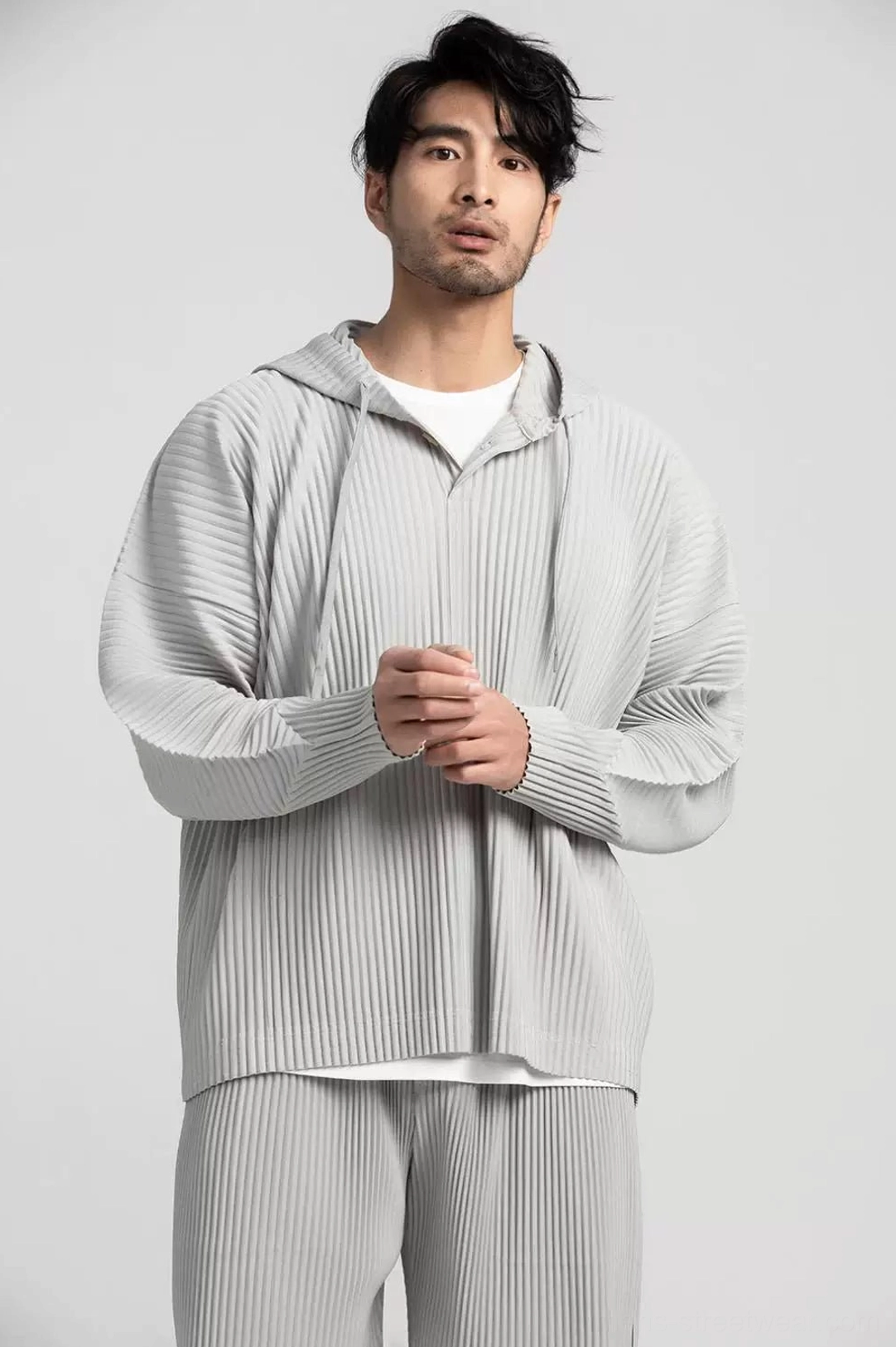 Light grey oversized Glacier Wave pleated hoodie shown in a close front view with vertical pleats and minimalist half-zip streetwear detailing