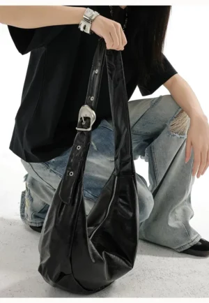 Glossy black crescent sling bag front view showing soft hobo silhouette adjustable eyelet strap and silver buckle