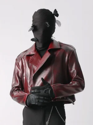 Glossy burgundy faux leather cropped moto jacket front three quarter view with wide lapels asymmetric closure shoulder epaulets and silver hardware
