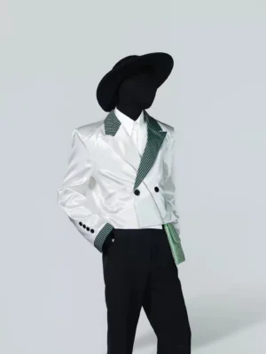 Front three-quarter view of a glossy white cropped tuxedo blazer with green houndstooth lapels and cuffs, styled with a matching chain-strap accent
