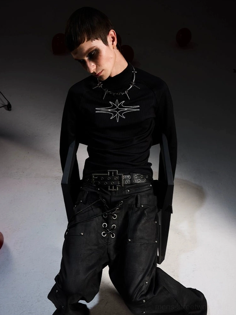 Side low angle view of fitted gothic black long sleeve mockneck top with silver star print and oversized lace-up cargo pants