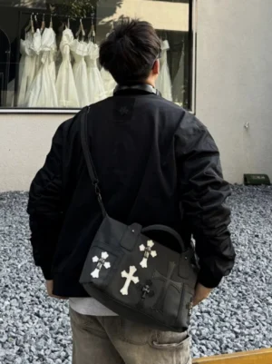 Black gothic cross PU leather crossbody satchel worn across the back with streetwear outfit outdoors