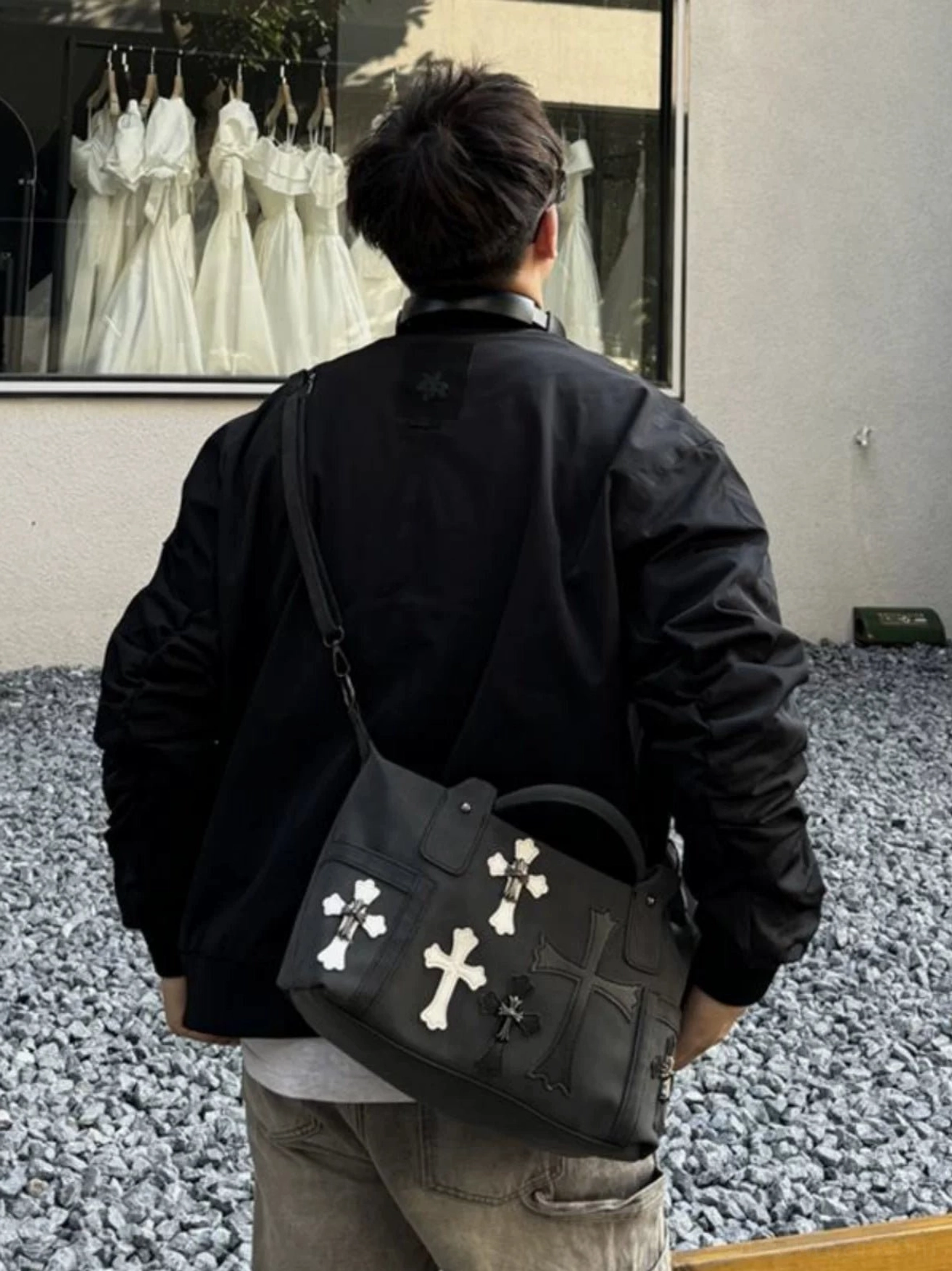 Black gothic cross PU leather crossbody satchel worn across the back with streetwear outfit outdoors