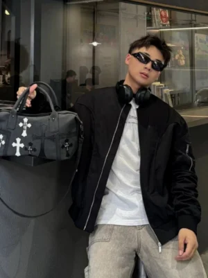 Black gothic cross PU leather satchel held by top handle in indoor streetwear cafe setting