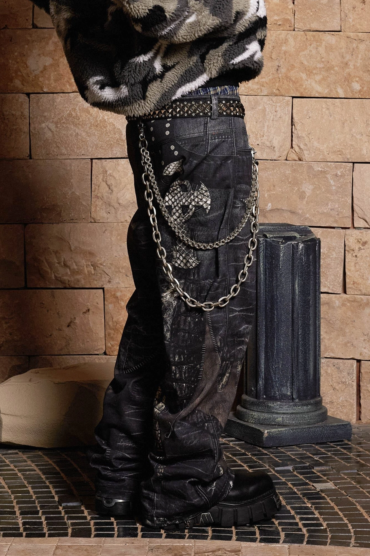 Side close-up of washed dark grey gothic dragon sword jeans with layered chains, side graphic prints, studded belt, and loose streetwear silhouette