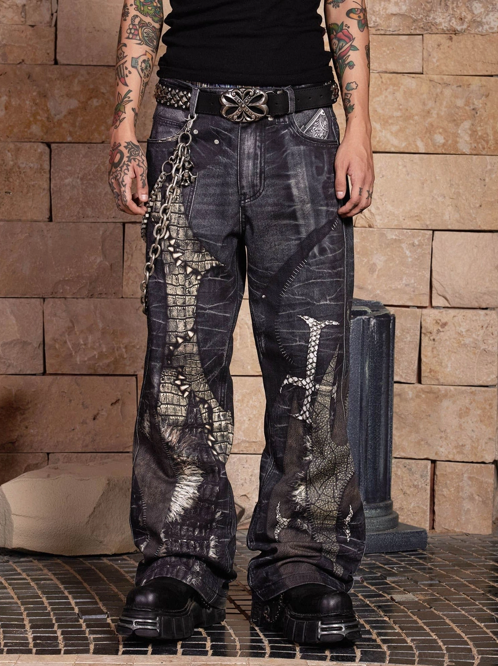 Front view of washed dark grey gothic dragon sword wide-leg jeans with crocodile-inspired graphics, metal chains, studded belt, and baggy streetwear fit