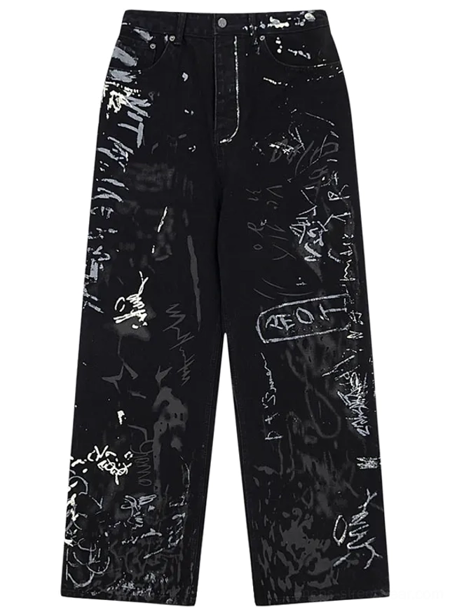 Graffiti print wide-leg black jeans front flat lay view showing all-over hand-drawn artwork and splatter ink designs on premium denim streetwear