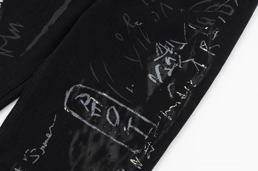 Graffiti wide-leg jeans close-up showing prominent AEOT tag graffiti mixed with handwritten text and abstract splatter designs on black denim