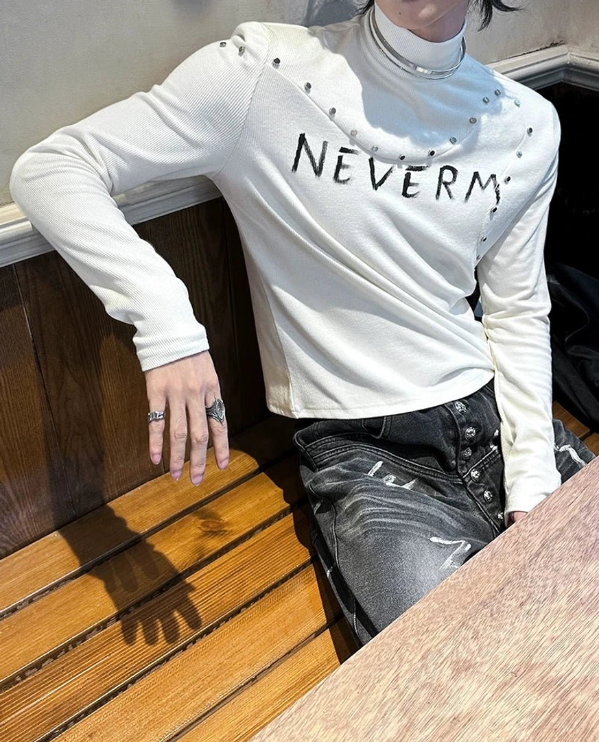 Graphic gothic turtleneck knit top with shoulder studs, high neck construction, and fitted long sleeve silhouette