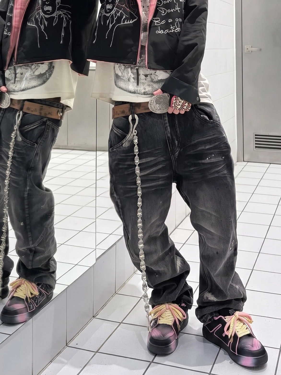 Matching black and pink chunky graphic sneakers worn with baggy streetwear outfits in a mirror view