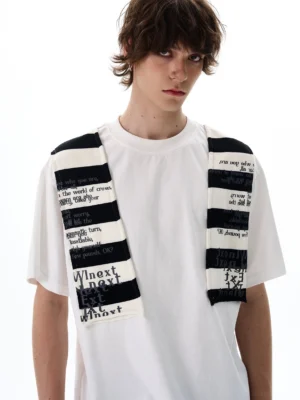 Close-up front view of a white graphic stripe patchwork tee with black striped typography panels across both shoulders