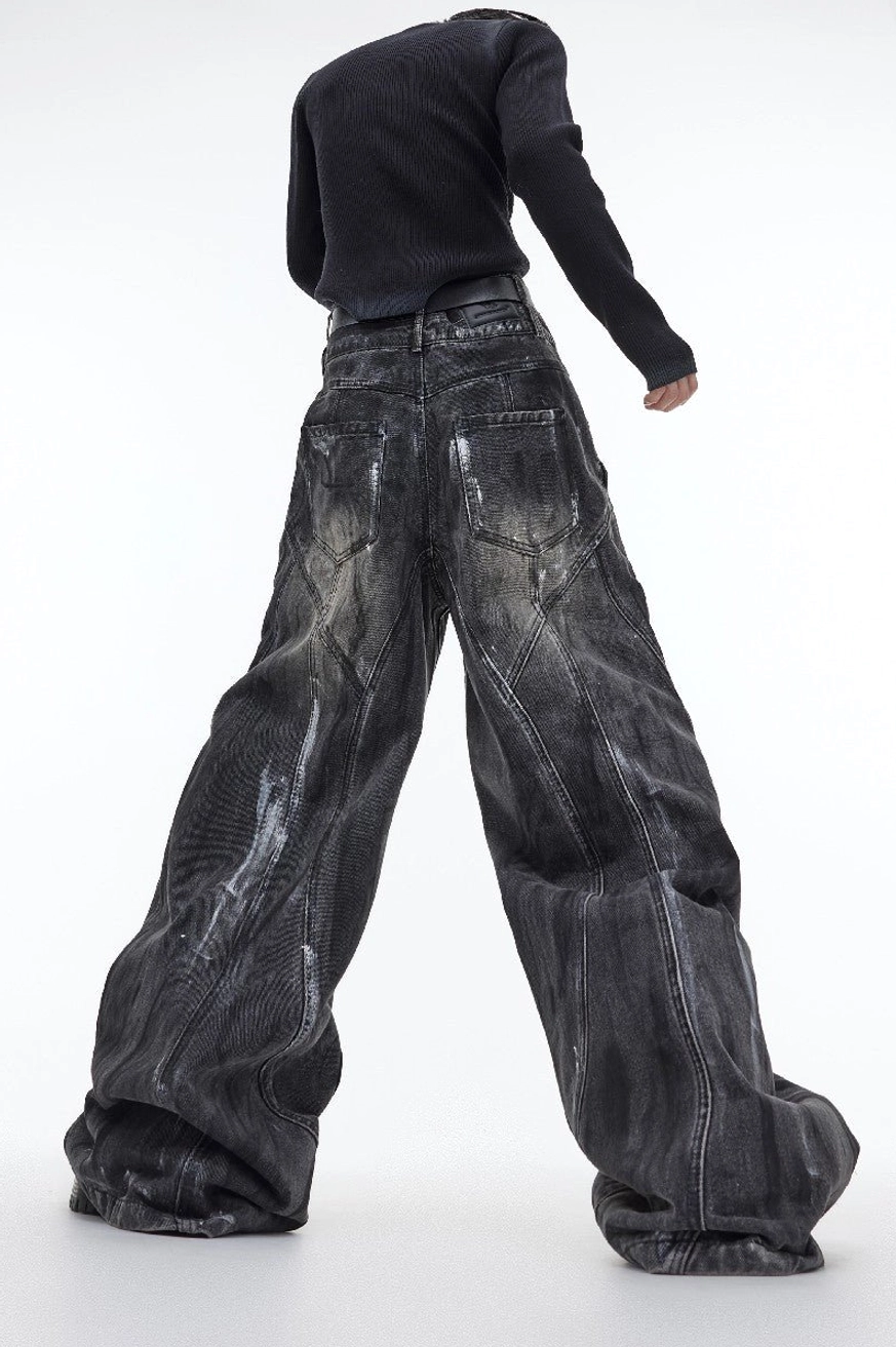 Rear view of oversized graphite black flared denim jeans with silver paint splatter distressing wide legs and decorative pocket seams
